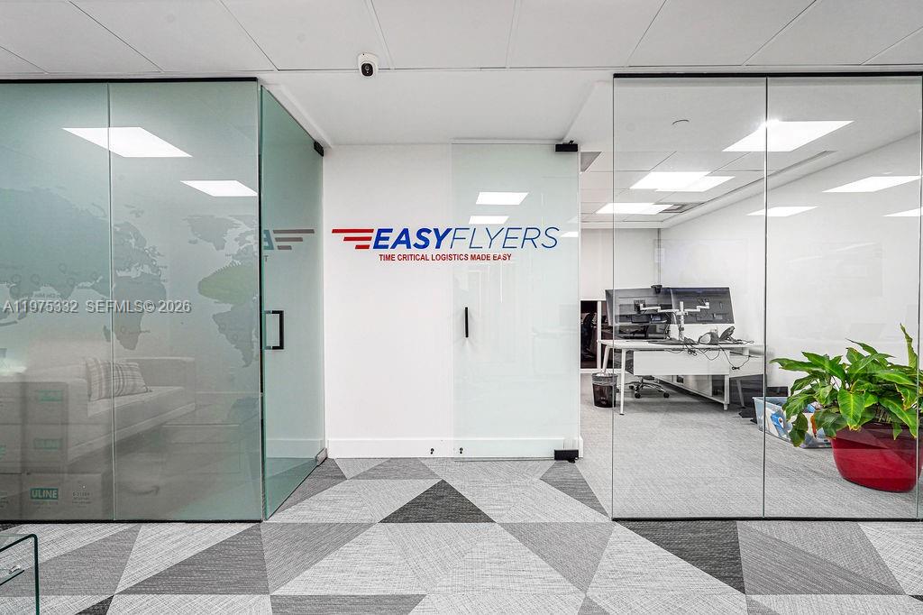 An office interior features glass-walled rooms, a company logo on the wall, and patterned carpeting — 1110 Brickell Ave # 700A, Miami FL 33131, MIAMI, FL