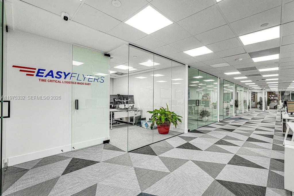 An office interior features glass-walled conference rooms and a geometric patterned carpet — 1110 Brickell Ave # 700A, Miami FL 33131, MIAMI, FL
