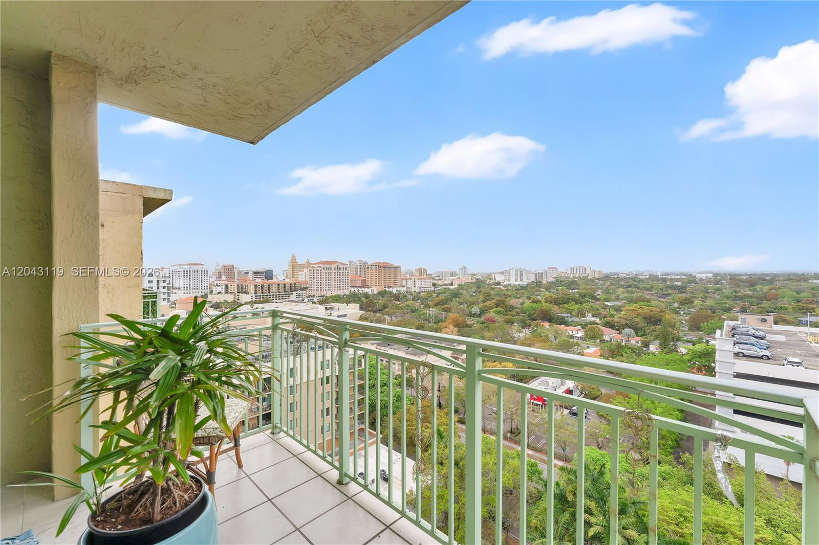 A balcony with a potted plant overlooks a city skyline and a parking structure — 3500 Coral Way # 10, Miami FL 33145, MIAMI, FL