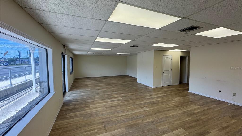 An empty commercial space features wood-look flooring, a drop ceiling with recessed lighting, and large windows — 4065 S SUNCOAST BOULEVARD, HOMOSASSA, FL