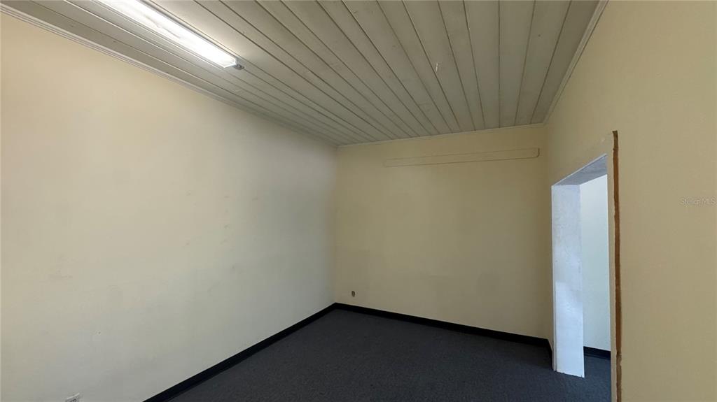 An empty room with beige walls, dark carpeting, and a white paneled ceiling — 4065 S SUNCOAST BOULEVARD, HOMOSASSA, FL