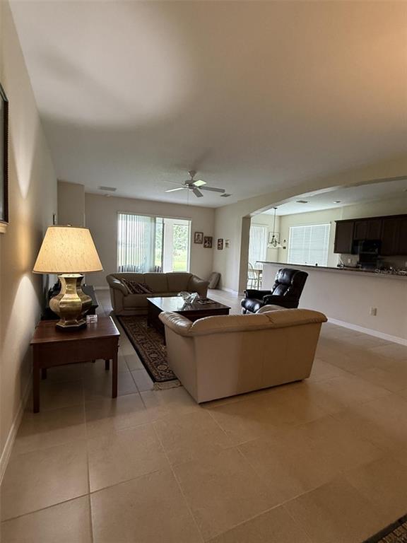 A living room with tile floors, a ceiling fan, and an open kitchen with dark cabinets — 4546 SHENANDOAH RIVER TRAIL, LEESBURG, FL