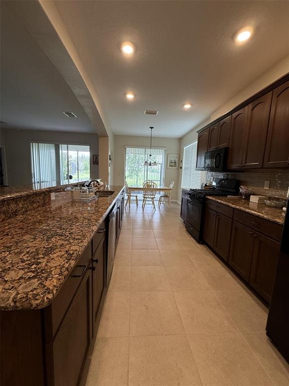 A kitchen with dark wood cabinets, granite countertops, and a dining area in the background — 4546 SHENANDOAH RIVER TRAIL, LEESBURG, FL