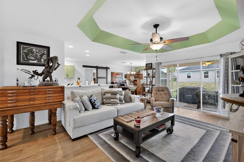 A living room features a tray ceiling with green trim, a sofa, and a coffee table — 11367 LAUFERSKY LANE, OXFORD, FL