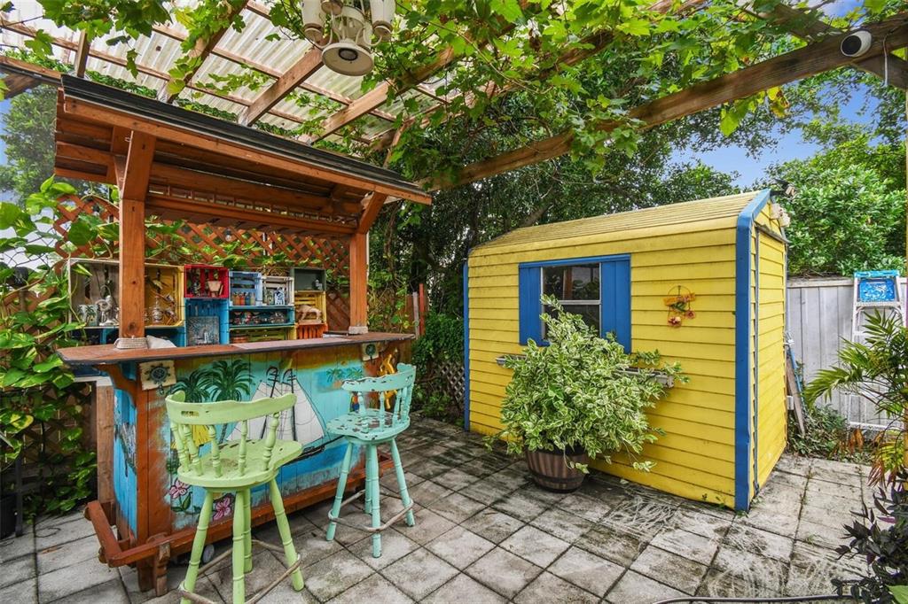 A patio features a blue dining set under a pergola with a light blue umbrella — 1627 DANDER DRIVE, HOLIDAY, FL