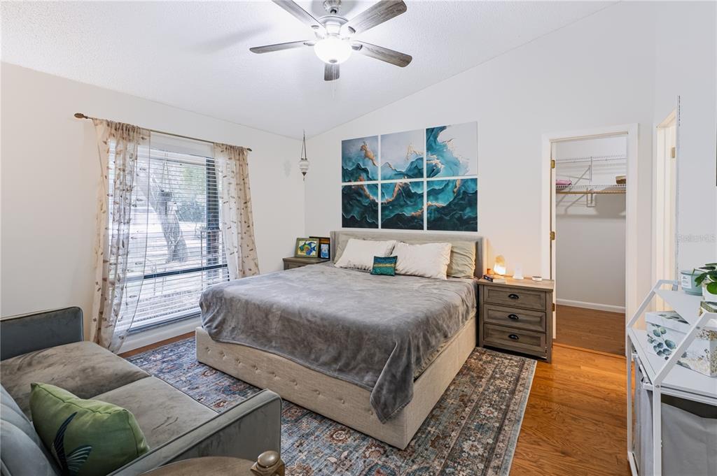 A bedroom features a bed with a gray blanket, a ceiling fan, and wall art — 241 RUTH BOULEVARD, LONGWOOD, FL