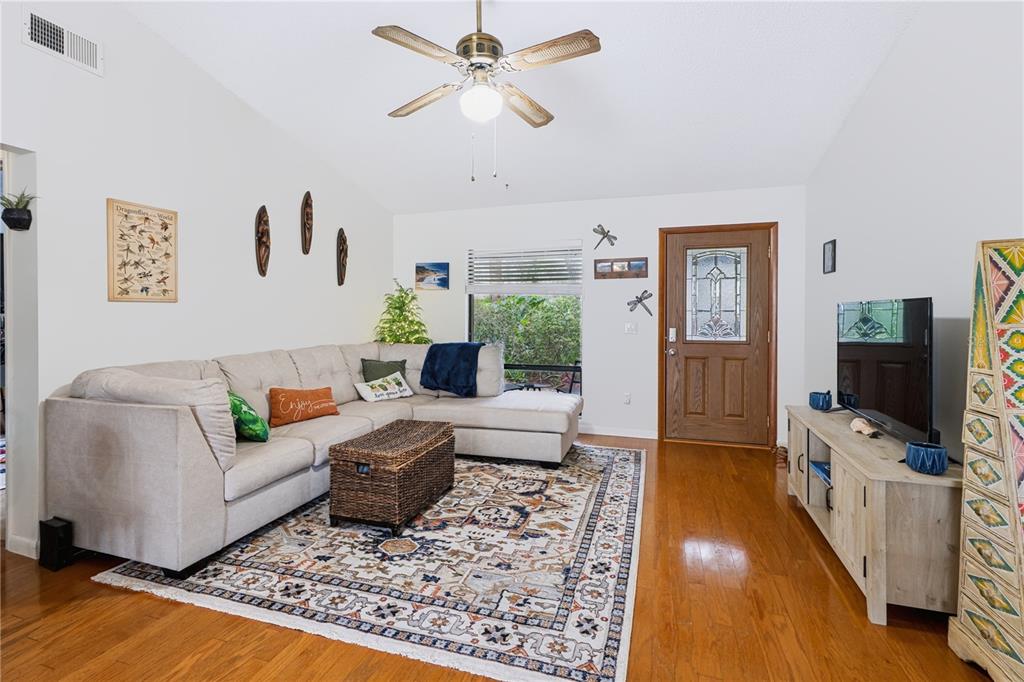A living room features a sectional sofa, a patterned area rug, and hardwood flooring — 241 RUTH BOULEVARD, LONGWOOD, FL