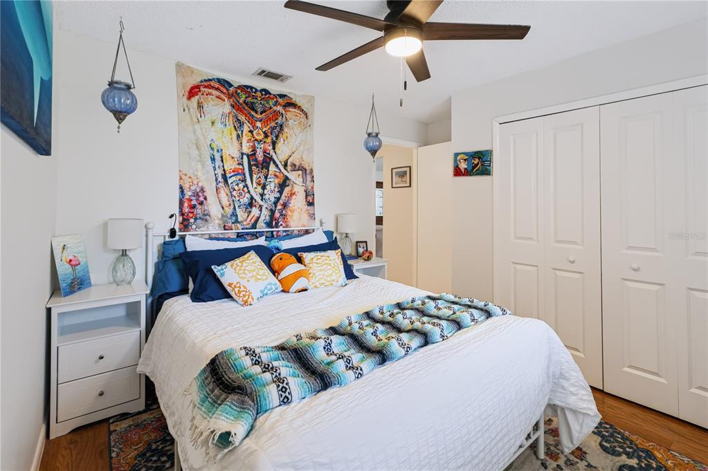 A bedroom features a bed with an elephant tapestry, a ceiling fan, and white furniture — 241 RUTH BOULEVARD, LONGWOOD, FL
