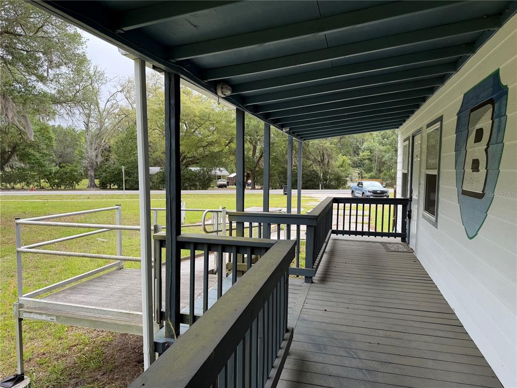 A covered wooden porch features a metal wheelchair ramp and a painted shield emblem — 683 N COURT STREET, BRONSON, FL