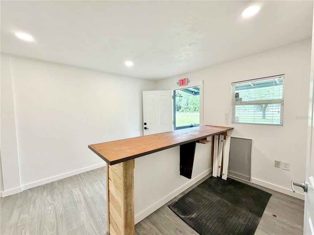 A room with light wood-look flooring, white walls, recessed lighting, and a wooden bar counter — 683 N COURT STREET, BRONSON, FL