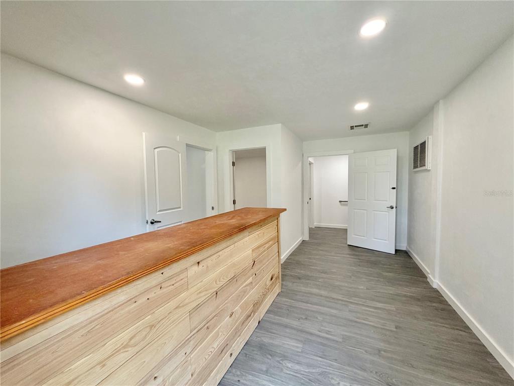 A room with light wood paneling, gray flooring, recessed lighting, and multiple white doors — 683 N COURT STREET, BRONSON, FL