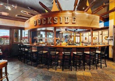 A restaurant bar area features wooden cabinetry, bar stools, and nautical-themed ceiling decorations — 102 RIVIERA DUNES WAY UNIT S-88, PALMETTO, FL