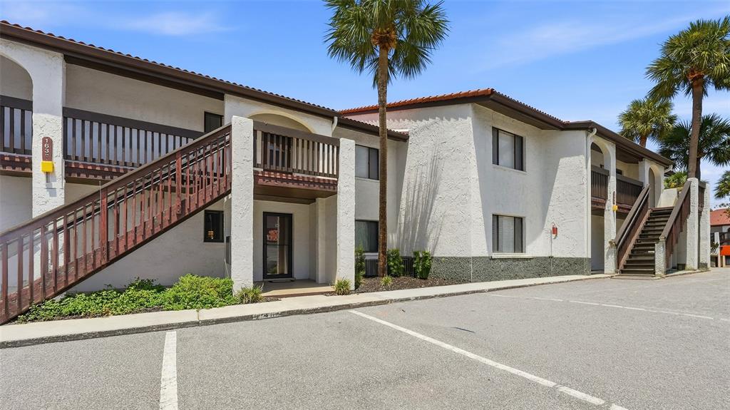 A two-story apartment building with white stucco walls, brown wooden railings, and a parking lot — 1638 STICKNEY POINT ROAD UNIT 38-102, SARASOTA, FL