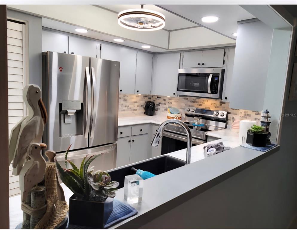 A kitchen features stainless steel appliances, light gray cabinets, and a dark sink — 8141 BUGLE COURT UNIT 2, PORT RICHEY, FL