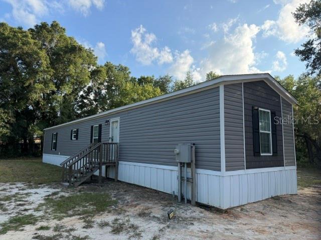 A single-story manufactured home with gray horizontal siding and a white skirting base — 113 MAGNOLIA AVENUE, HAWTHORNE, FL