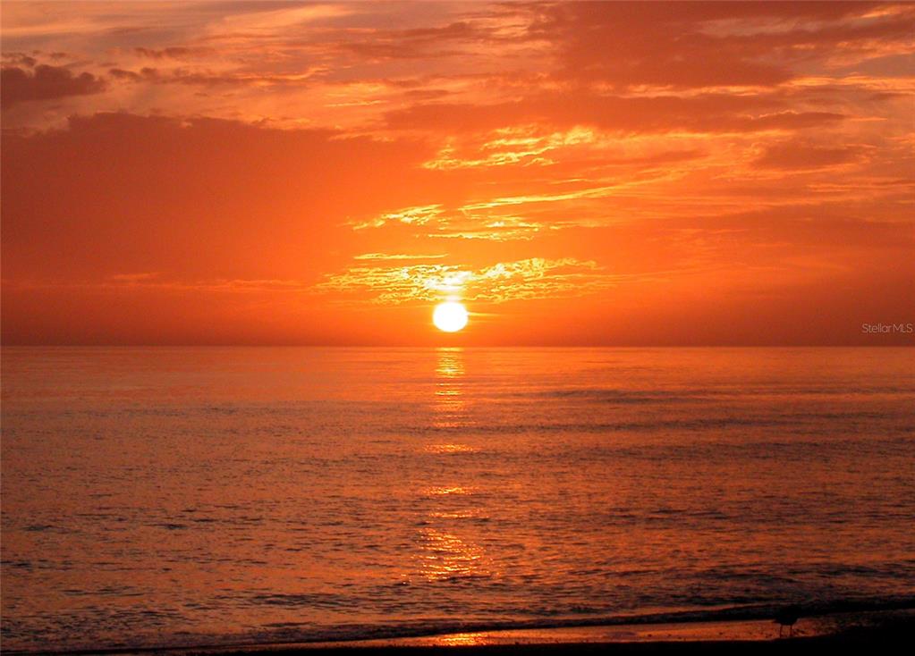 A vibrant orange sunset glows over the ocean horizon with a reflection on the water — 7115 GULF OF MEXICO DRIVE UNIT 23, LONGBOAT KEY, FL