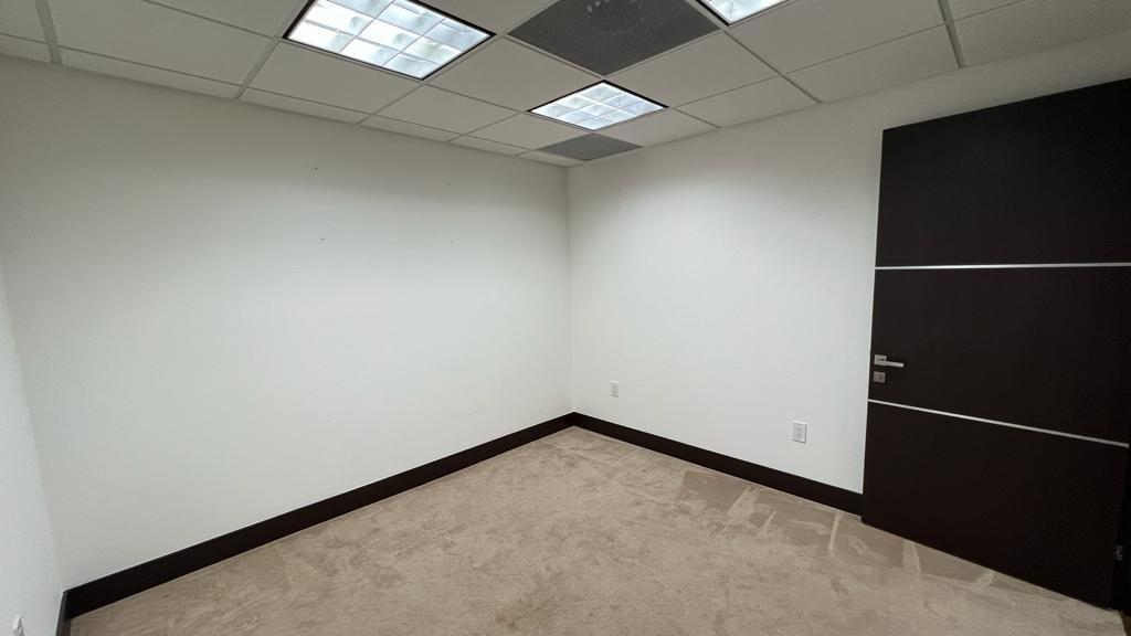 An empty office room features white walls, beige carpeting, a dark door, and drop ceiling tiles — 2730 SW 3rd Avenue # 202N, Miami FL 33129, MIAMI, FL