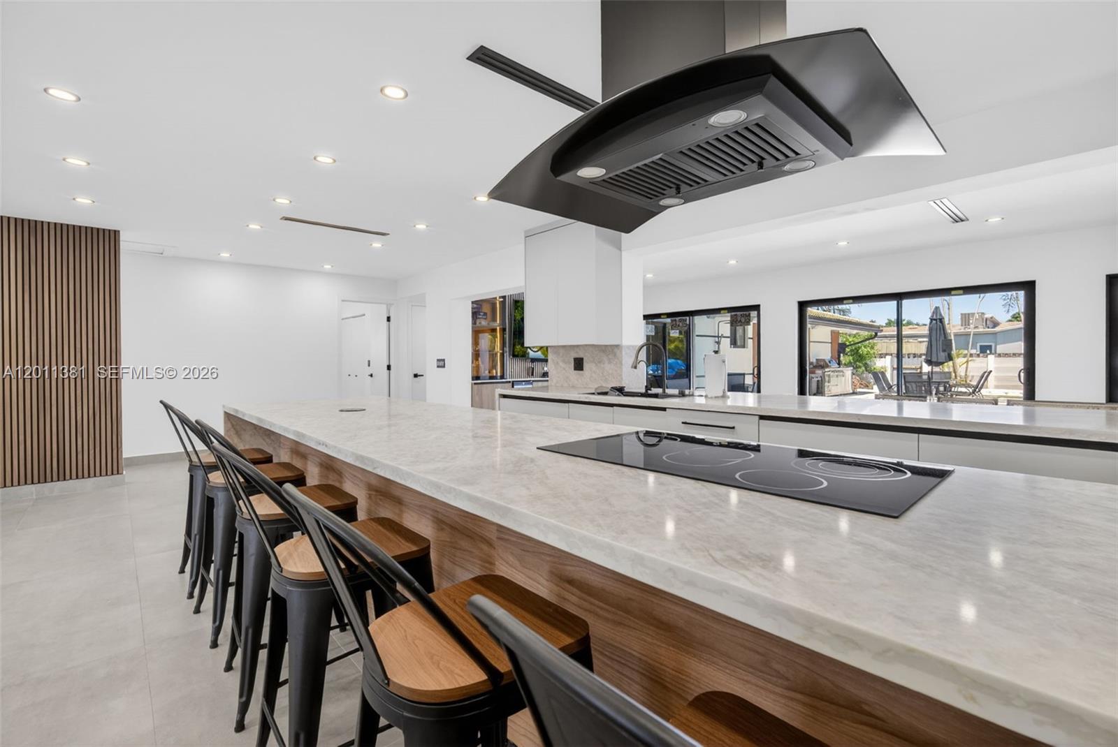 A modern kitchen features a large marble-topped island with bar stools and a black hood — 2131 N 53rd Ave, Hollywood FL 33021, HOLLYWOOD, FL