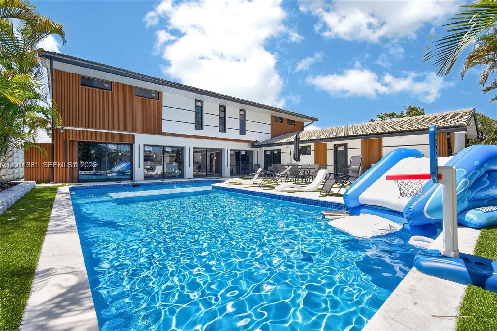 A modern two-story house features a swimming pool with an inflatable slide and basketball hoop — 2131 N 53rd Ave, Hollywood FL 33021, HOLLYWOOD, FL