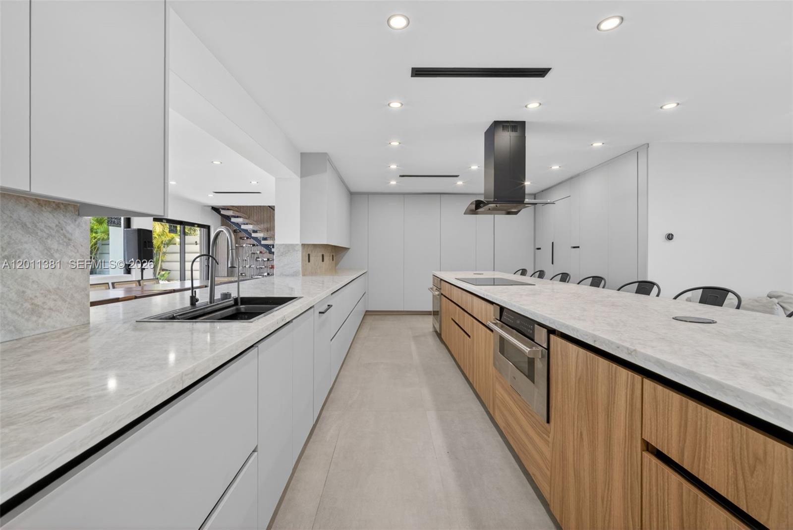 A modern kitchen features light gray cabinetry, wood-paneled island drawers, and white marble countertops — 2131 N 53rd Ave, Hollywood FL 33021, HOLLYWOOD, FL