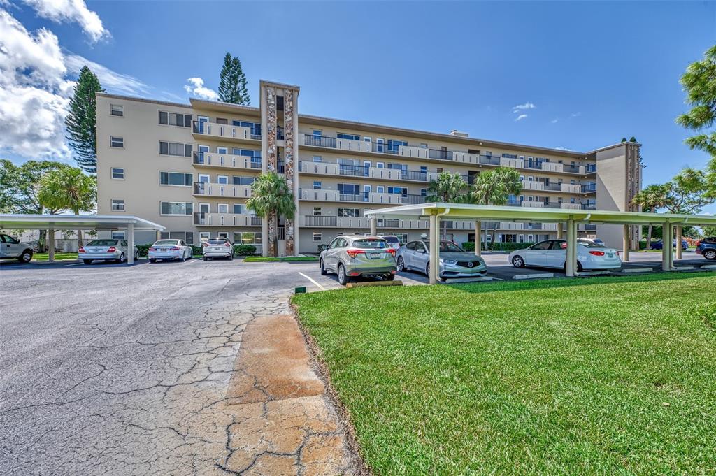 A multi-story apartment building with covered parking spaces and a grassy lawn in front — 4460 IRONWOOD CIRCLE UNIT 102A, BRADENTON, FL