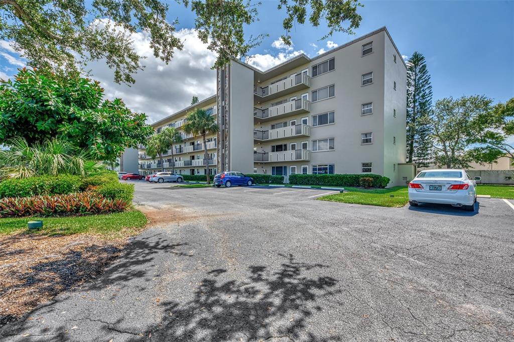 A multi-story apartment building features balconies and a parking lot with several parked cars — 4460 IRONWOOD CIRCLE UNIT 102A, BRADENTON, FL