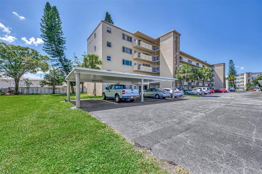 A multi-story apartment building features a covered parking area with several parked vehicles — 4460 IRONWOOD CIRCLE UNIT 102A, BRADENTON, FL