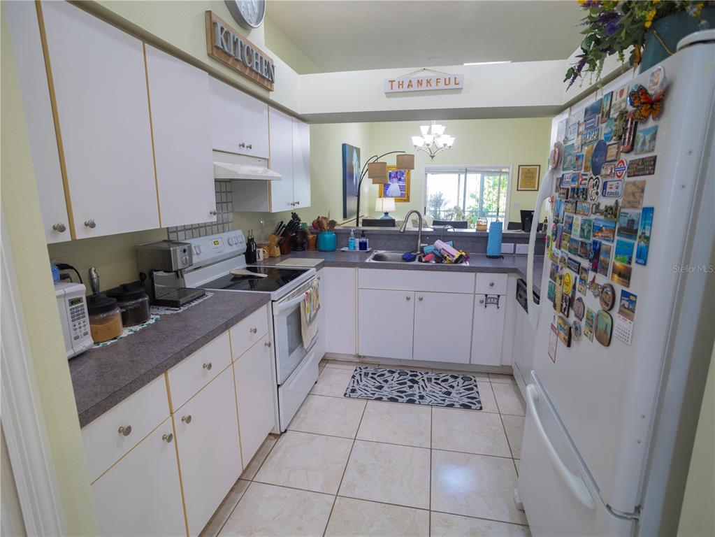 A kitchen with white cabinets, dark countertops, white appliances, and a tiled floor — 12537 HOLLYBROOK LANE, HUDSON, FL
