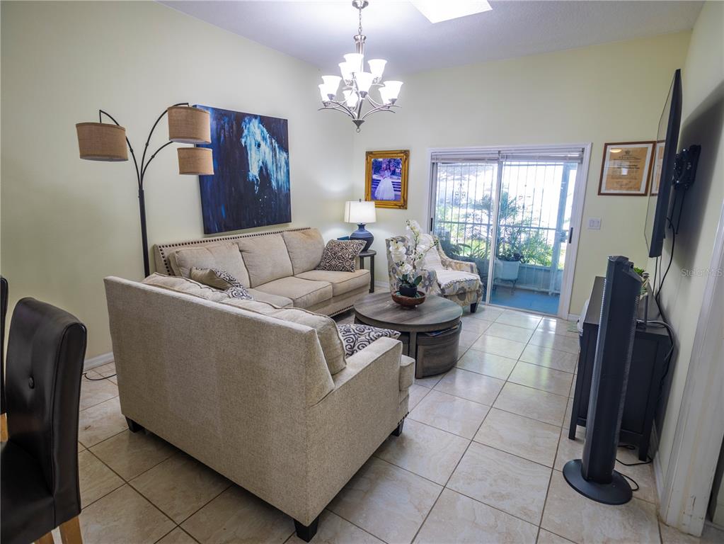 A living room features beige sofas, a round coffee table, tile flooring, and sliding doors — 12537 HOLLYBROOK LANE, HUDSON, FL