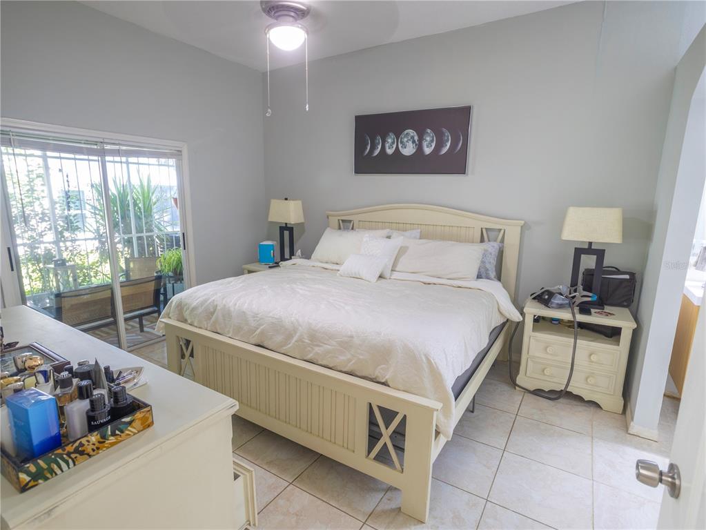A bedroom features a light-colored bed, two nightstands, a dresser, and sliding glass patio doors — 12537 HOLLYBROOK LANE, HUDSON, FL