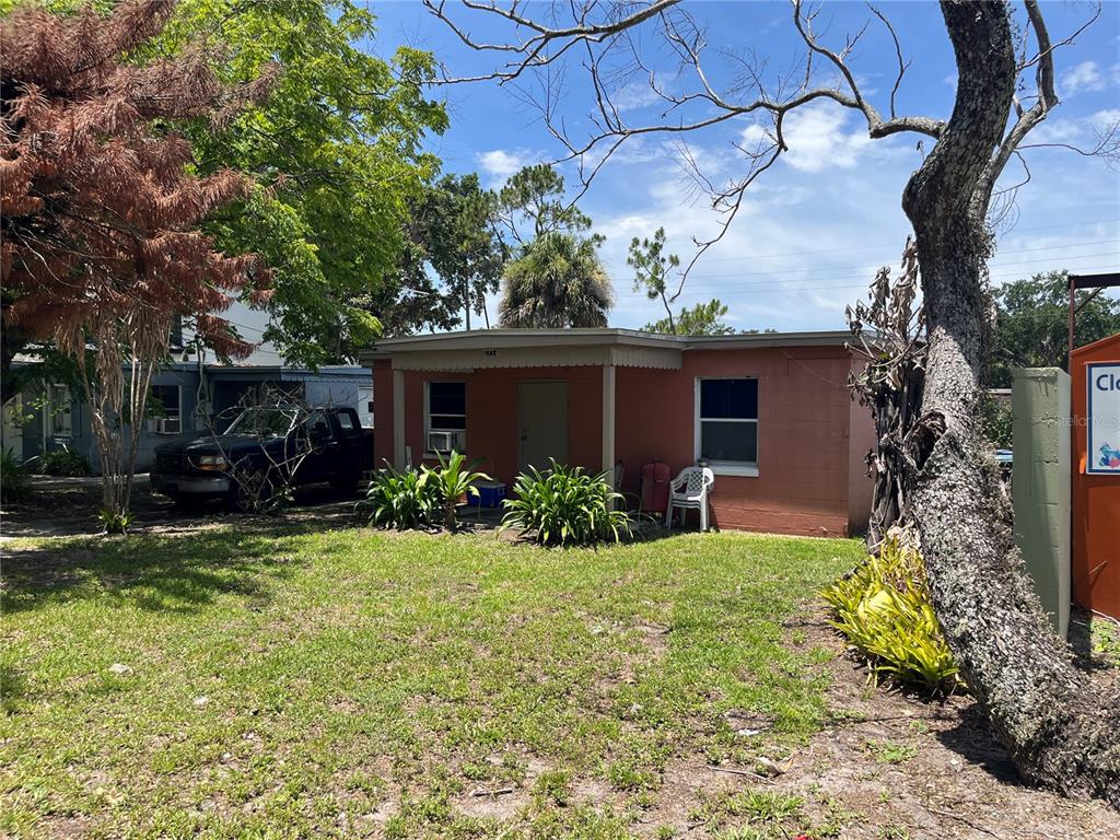 A single-story, peach-colored house with a covered front porch sits on a grassy lot — 884 E MICHIGAN STREET, ORLANDO, FL