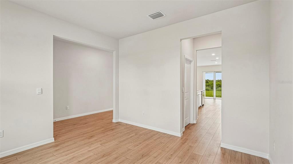 An interior view shows a room with light wood-look flooring and two arched doorways — 2838 FISHERY COURT, LAKEWOOD RANCH, FL