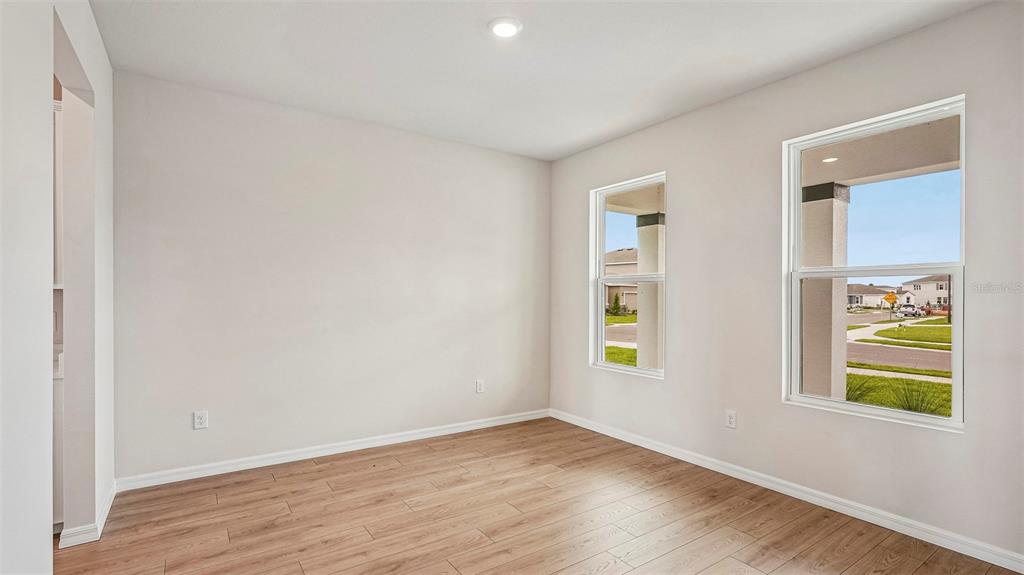 An empty room with light-colored walls, wood-look flooring, and two windows overlooking a neighborhood — 2838 FISHERY COURT, LAKEWOOD RANCH, FL