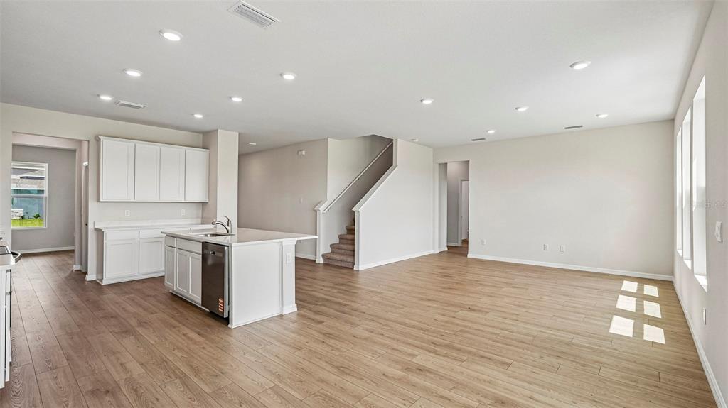 An open-concept kitchen and living area feature white cabinets, a center island, and wood flooring — 2838 FISHERY COURT, LAKEWOOD RANCH, FL