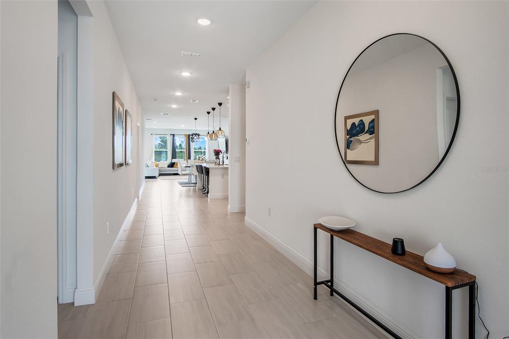 A long hallway with tile flooring leads to an open-concept kitchen and living area — 18863 RAWSON STREET, ORLANDO, FL