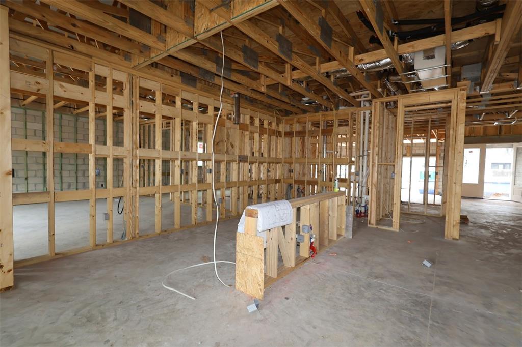 An unfinished room features concrete block walls, exposed wooden roof trusses, and a stack of drywall — 2670 RAVENCLIFFE TERRACE, OVIEDO, FL