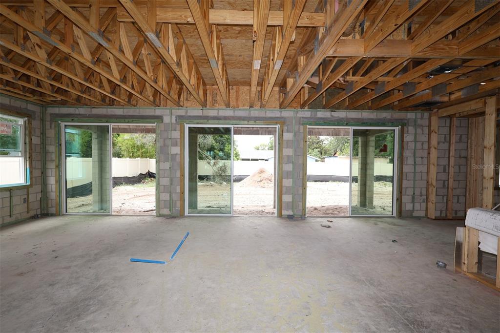 An unfinished room features concrete block walls, exposed wooden ceiling trusses, and three installed windows — 2670 RAVENCLIFFE TERRACE, OVIEDO, FL