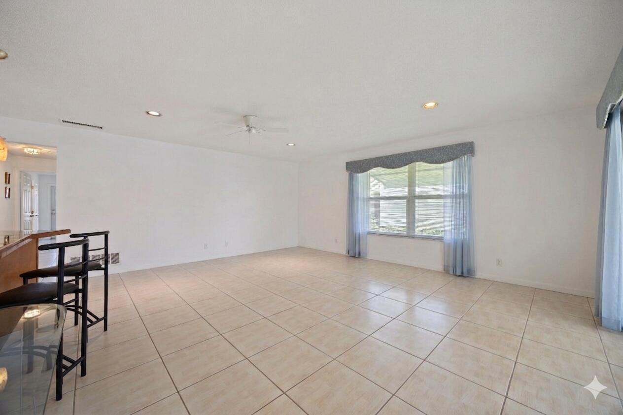 An empty living room with light-colored tile flooring, white walls, and a large window — 275 High Point Court # D, Boynton Beach FL 33435, BOYNTON BEACH, FL