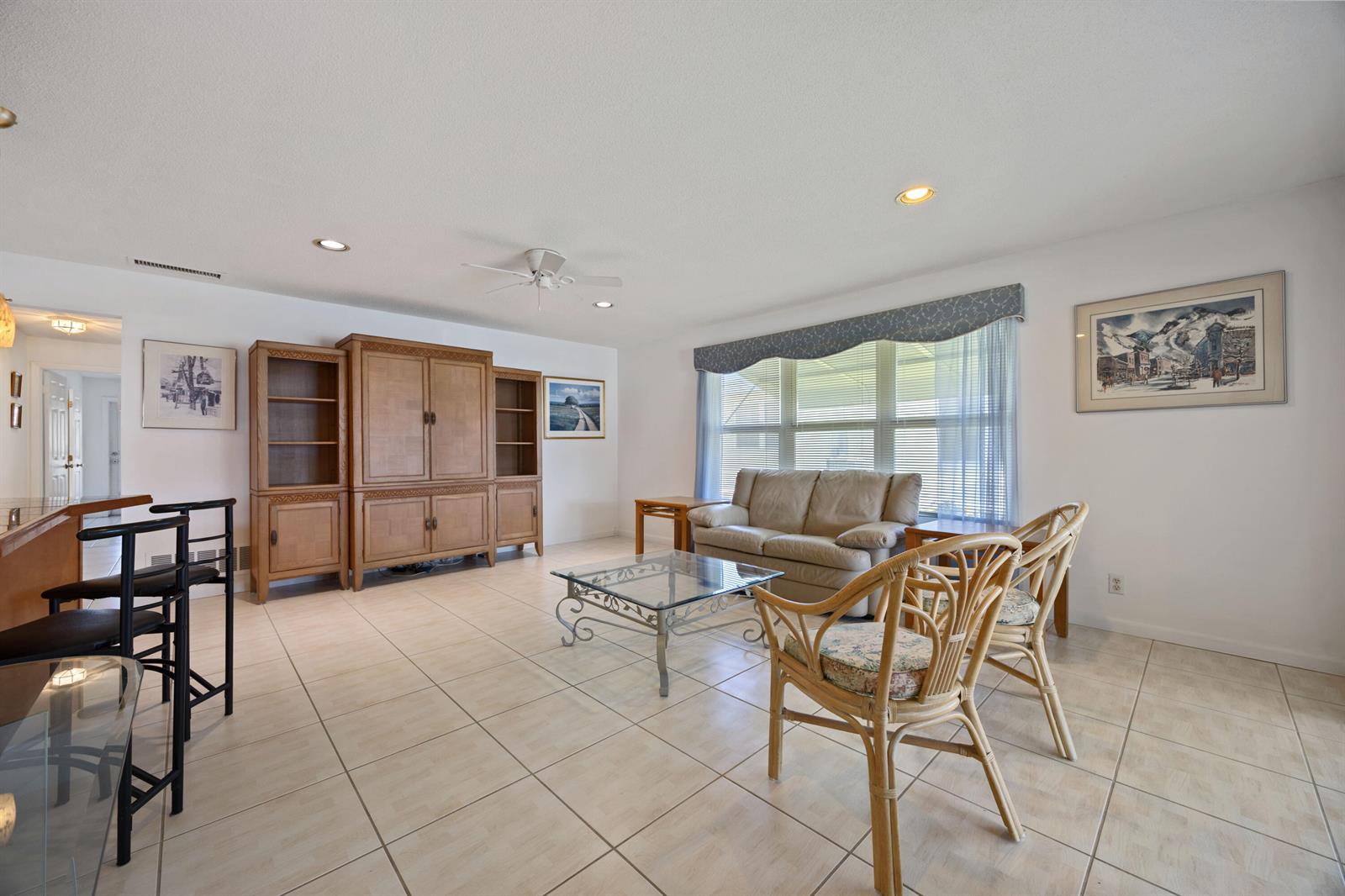 A living room featuring tile flooring, a large wooden entertainment center, and a beige sofa — 275 High Point Court # D, Boynton Beach FL 33435, BOYNTON BEACH, FL