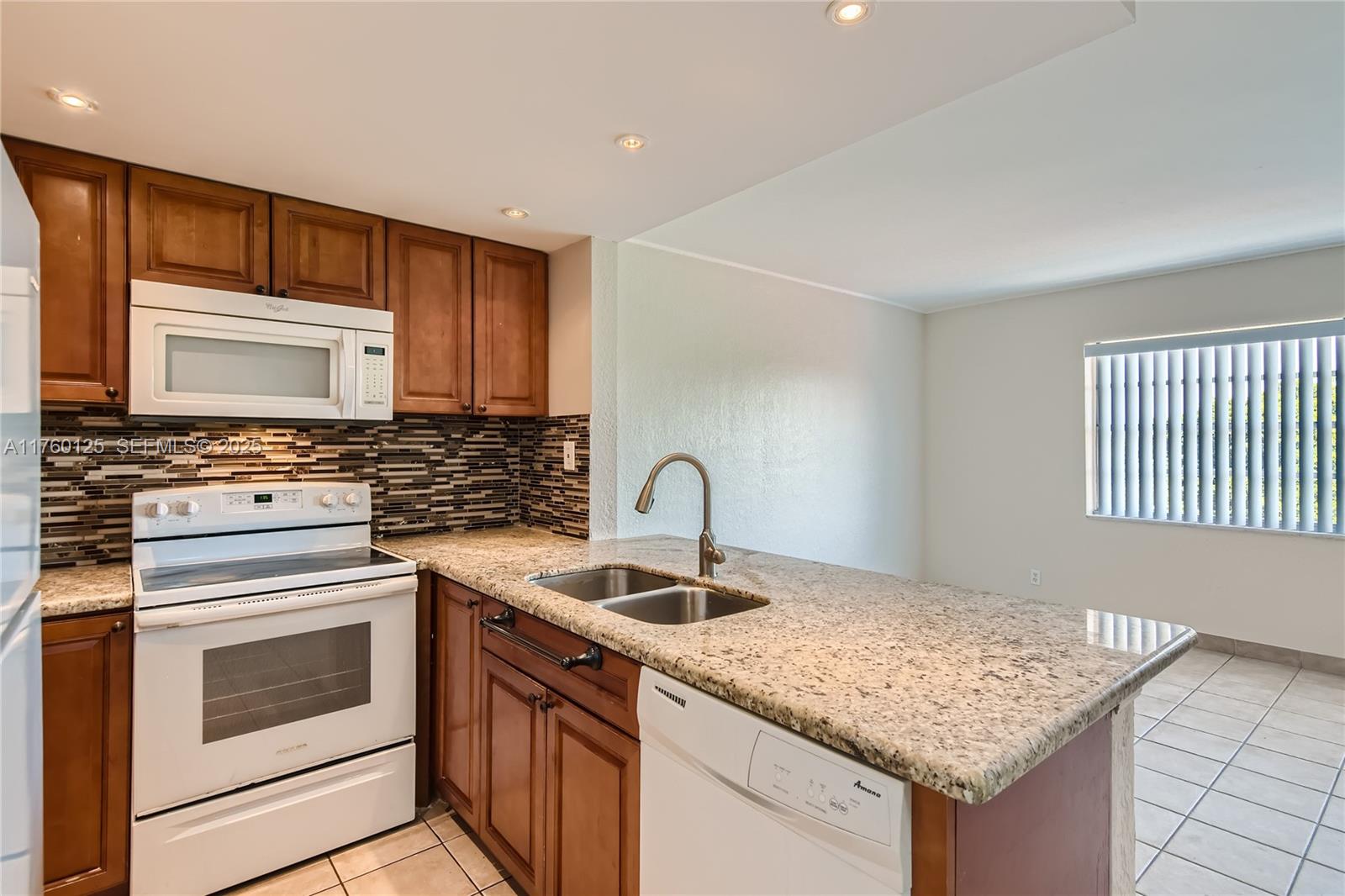 A kitchen features wood cabinets, granite countertops, white appliances, and a tiled floor — 1855 Plunkett St # 406, Hollywood FL 33020, HOLLYWOOD, FL