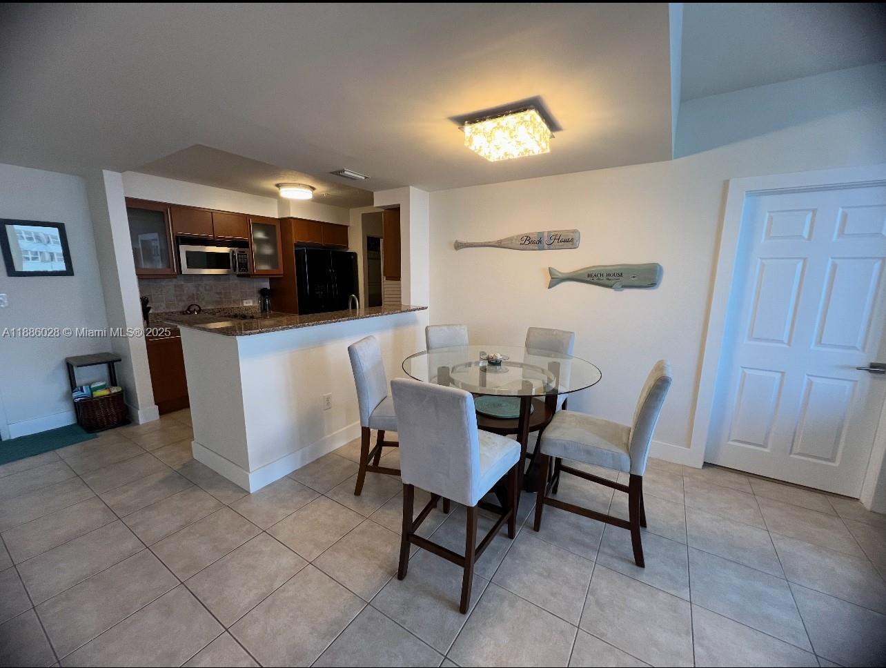 A dining area with a glass table and four chairs sits adjacent to a kitchen — 2080 S Ocean Dr, Hallandale Beach FL 33009, HALLANDALE BEACH, FL