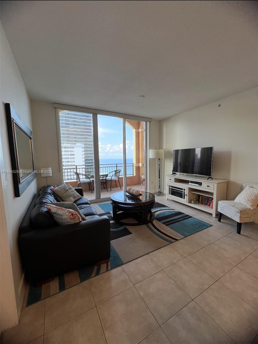 A living room features a dark sofa, a patterned rug, and a balcony with ocean views — 2080 S Ocean Dr, Hallandale Beach FL 33009, HALLANDALE BEACH, FL
