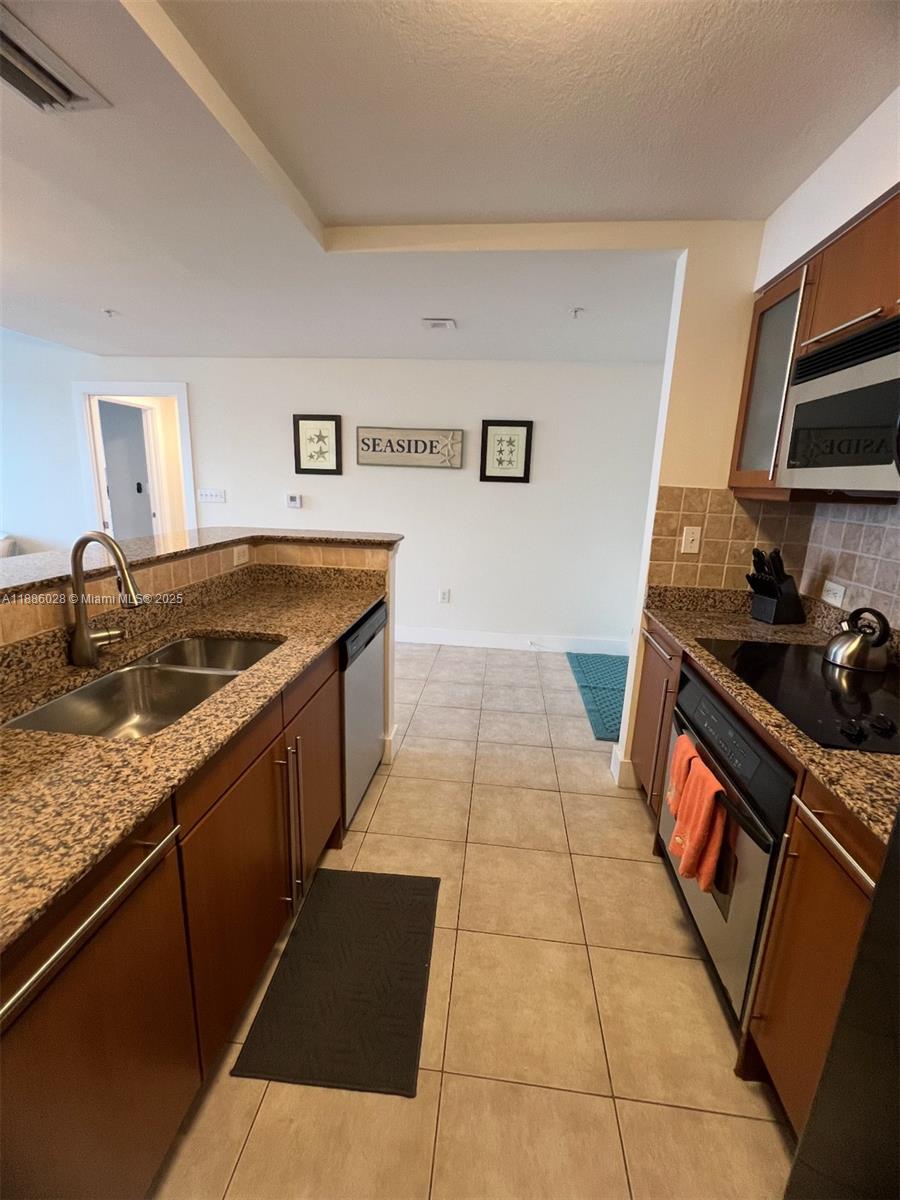A kitchen features granite countertops, wood cabinets, stainless steel appliances, and beige tile flooring — 2080 S Ocean Dr, Hallandale Beach FL 33009, HALLANDALE BEACH, FL
