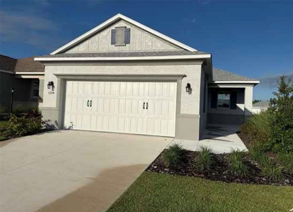 A single-story house exterior features a two-car garage, light stucco walls, and a gabled roof — 7204 SW 89TH AVENUE, OCALA, FL