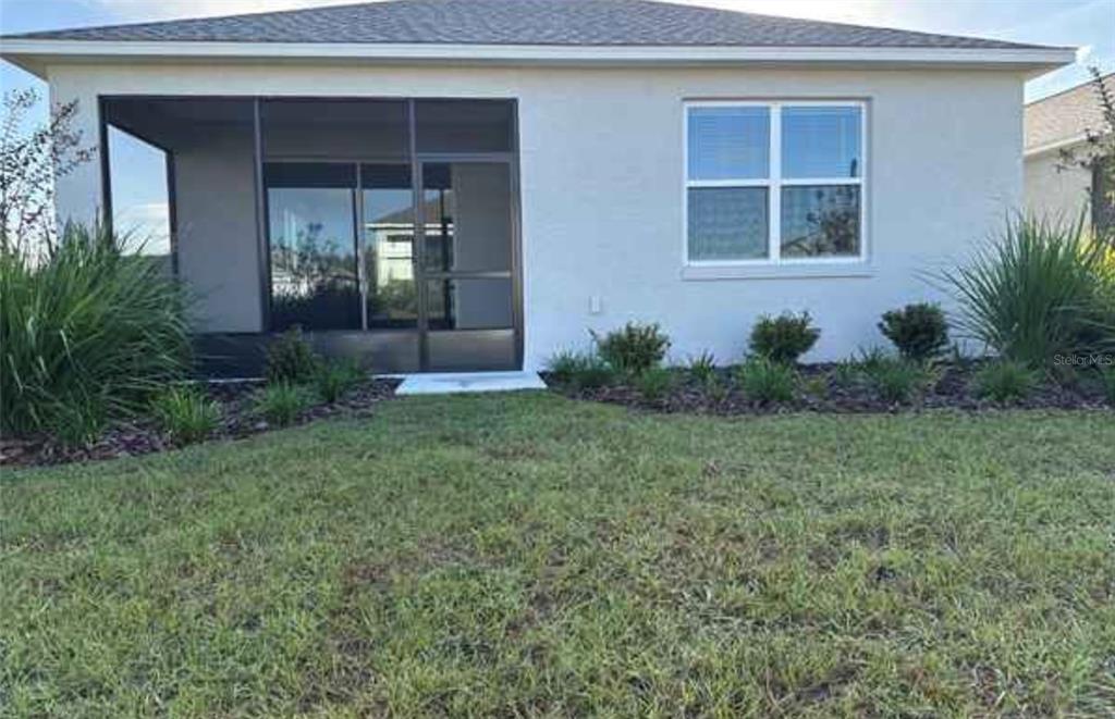 The exterior rear view of a house features a screened-in porch and a single window — 7204 SW 89TH AVENUE, OCALA, FL