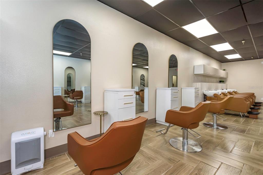 A hair salon features multiple styling stations with arched mirrors, tan chairs, and tile flooring — 2554 E BEARSS AVENUE, TAMPA, FL