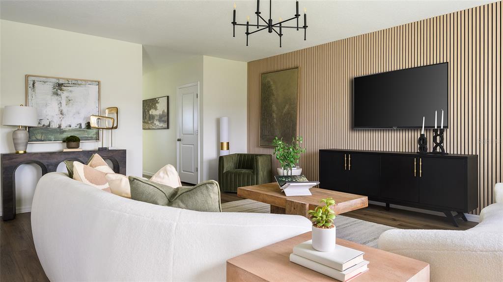 A living room features a slatted wood accent wall, a television, and modern furniture — 5444 SAN PIETRO DRIVE, WINTER HAVEN, FL