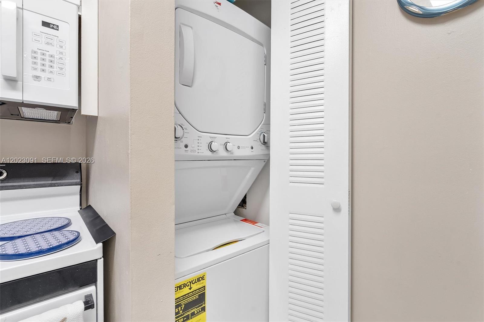 A stacked washer and dryer unit is located in a closet next to a stove — 15635 SW 74th Cir Dr # 11, Miami FL 33193, MIAMI, FL