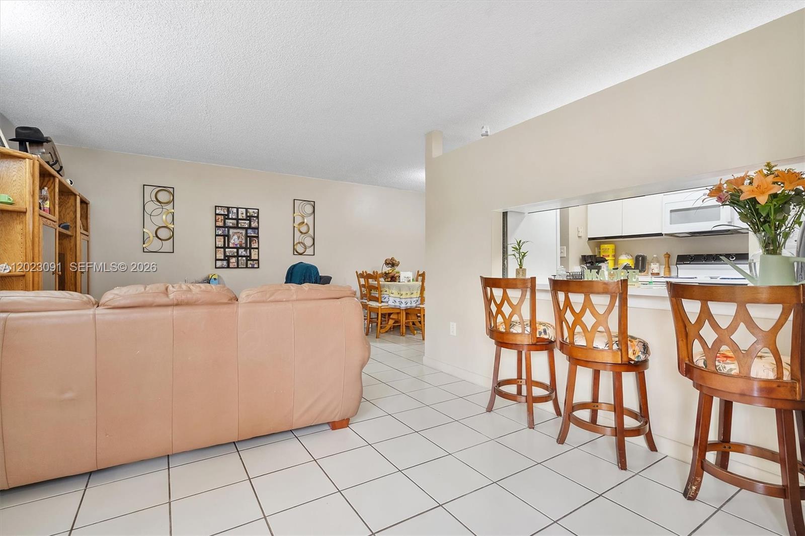A living room with a beige sofa, tile flooring, and a breakfast bar with stools — 15635 SW 74th Cir Dr # 11, Miami FL 33193, MIAMI, FL