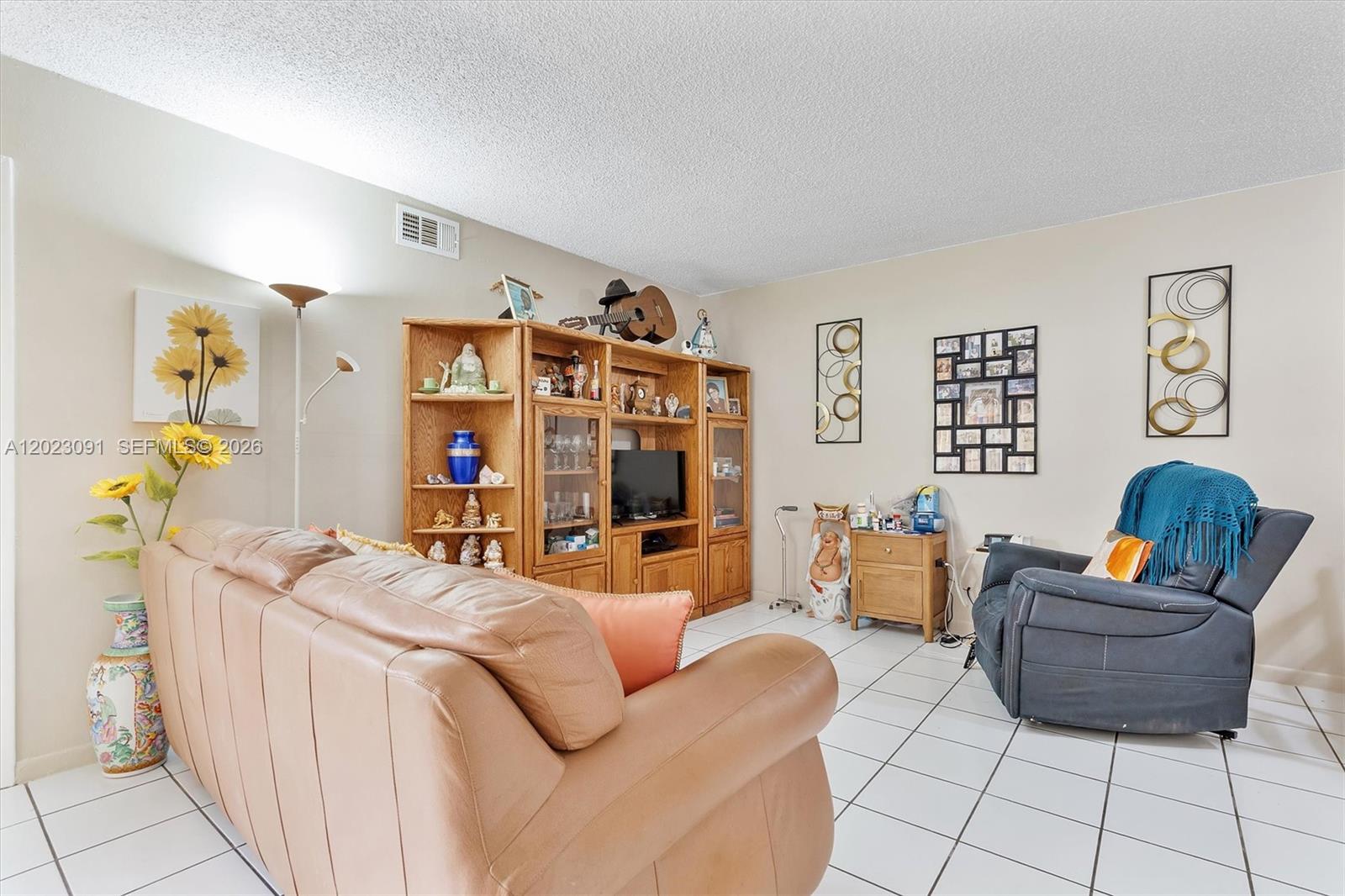 A living room features a tan leather sofa, a wooden entertainment center, and tile flooring — 15635 SW 74th Cir Dr # 11, Miami FL 33193, MIAMI, FL